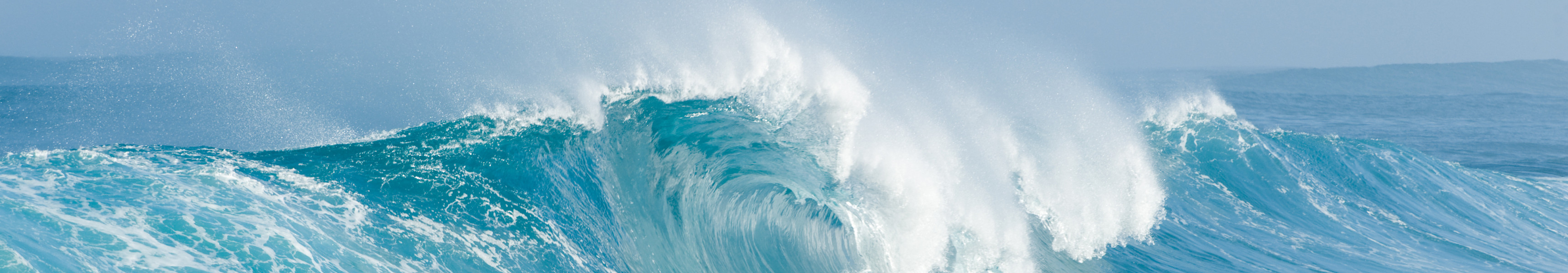 Große Welle bricht im eisblauen Meer