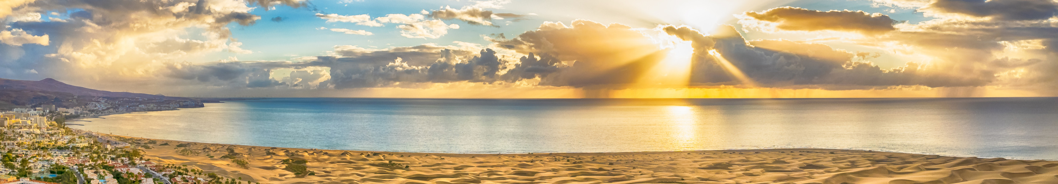 Sonnenuntergang über den Dünen von Maspalomas mit Blick auf das Meer und Hotels auf Gran Canaria.