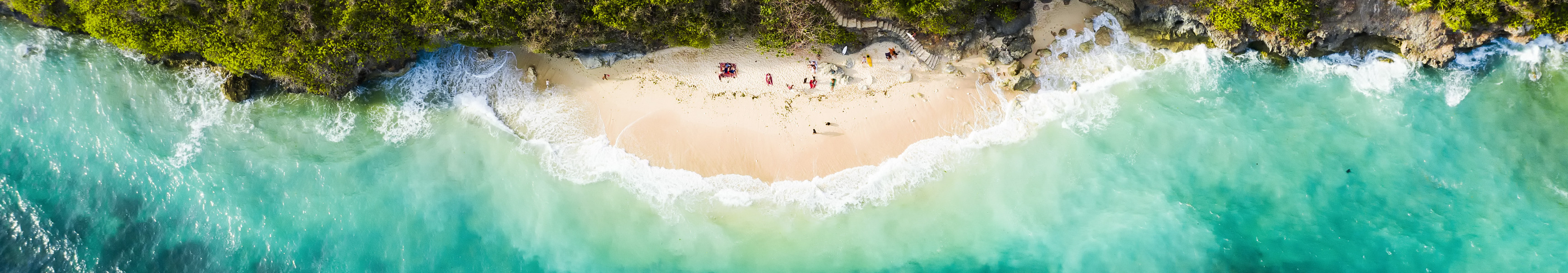 Atemberaubende Luftaufnahme einiger Touristen, die am wunderschönen Green Bowl Beach im Süden von Bali, Indonesien, sonnenbaden.