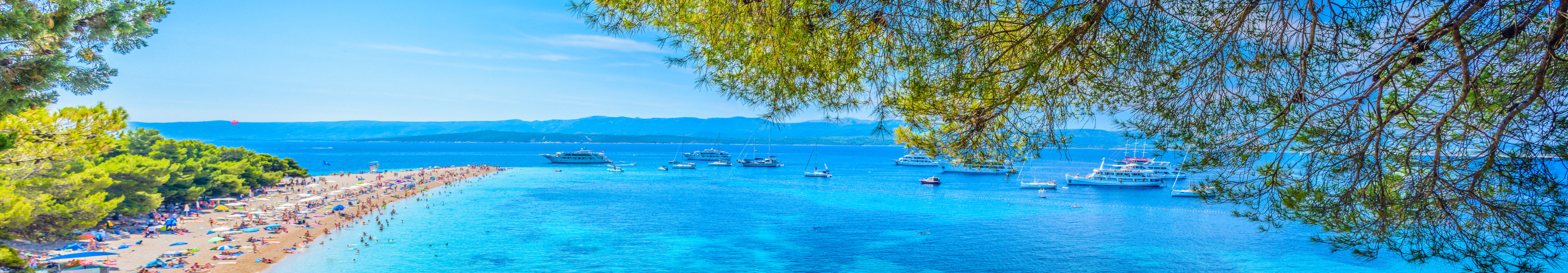Strand Zlatni Rat auf der Insel Brač in Kroatien, eine lange Landzunge mit feinem Sand, türkisfarbenem Wasser und Booten im Hintergrund.