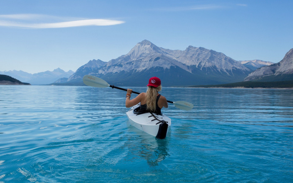 Frau fährt Kanu auf einem See mit Bergkulisse