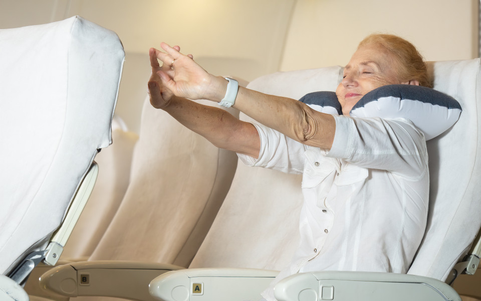 Frau streckt und bewegt sich bei einem Langstreckenflug