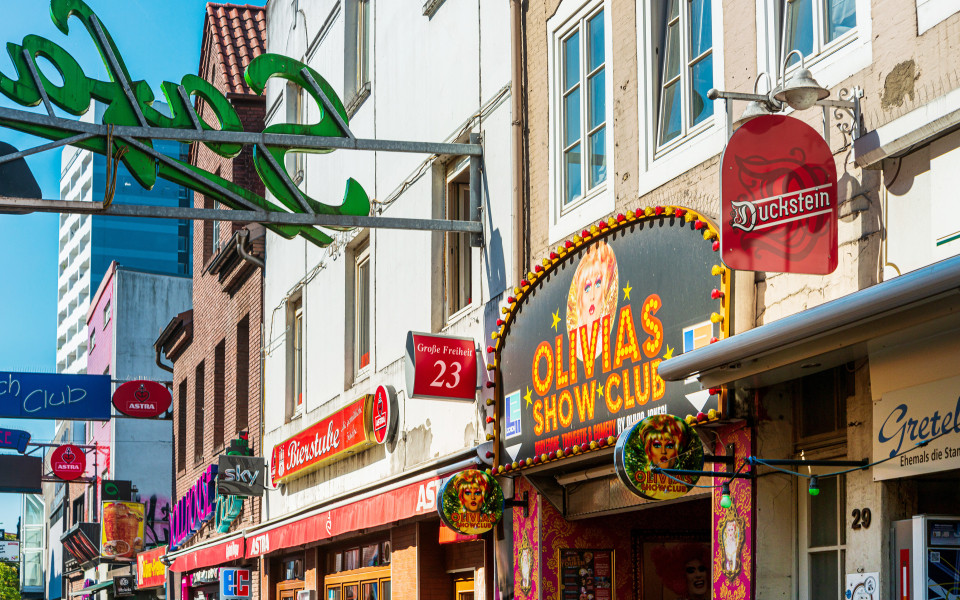 Große Freiheit auf der Reeperbahn in Hamburg, eine lebendige Straße mit Bars, Clubs und bunten Leuchtschildern, darunter Olivias Show Club.