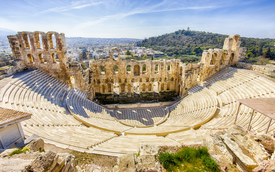 Blick auf das antike Theater von Herodes Atticus in Athen, mit einer beeindruckenden römischen Architektur und einer weiten Aussicht auf die Stadt und die umliegenden Hügel.