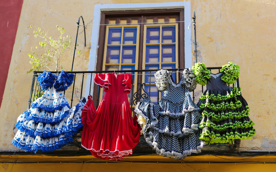 Bunte Flamenco-Kleider hängen von einem Balkon in Andalusien