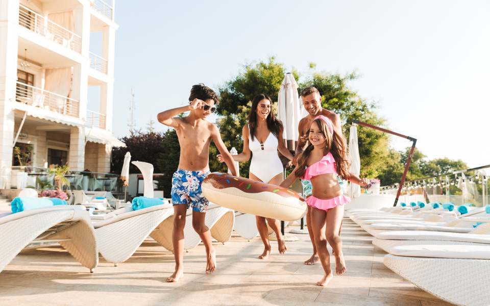 Familie mit Kindern, die sich an einem Hotel Swimmingpool entspannen.