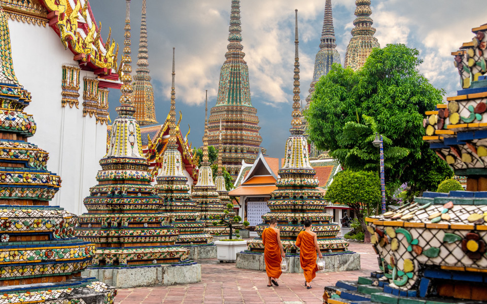 Zwei Mönche gehen an Stupas im Wat Pho Tempel in Bangkok entlang.